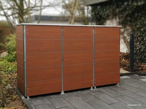 . The image shows a wooden storage unit or cabinet located outdoors on a tiled patio. The unit appears to have a sleek, modern design with metal accents. It is surrounded by a garden area with plants and trees in the background.