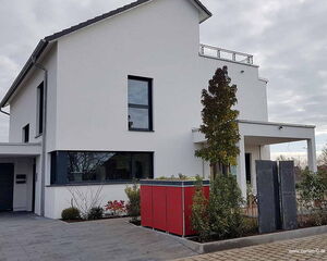 Modernes zweistöckiges Haus mit weißer Fassade, großen Fenstern, kleinem Garten und rotem Schuppen.