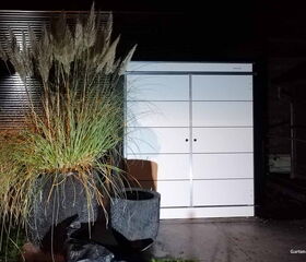 . Ein modernes Gartenschrank mit dekorativen Pflanzen daneben, nachts fotografiert.