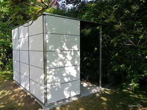 . Ein modernes Gartenhaus mit weißen Paneelen, umgeben von Bäumen im Schatten.