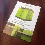 The image shows a brochure or booklet with an image of a green, modern structure on the cover. The text in German mentions modern garden buildings and furniture for kids and kindergartens.