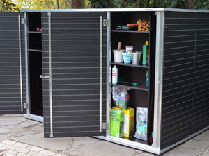 . Ein geöffneter Schuppen mit Regalen voller Gartenwerkzeuge und Produkten, umgeben von Pflanzen.