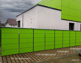 Grüne Abfall- und Kinderwagencontainer vor einem Gebäude. Beschriftungen: "1.100 Liter Müllcontainer" und "Kinderwagen".