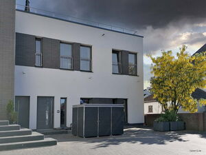 . Modernes Gebäude mit weißer Fassade, dunklen Fenstern und gelbem Baum im Vordergrund.