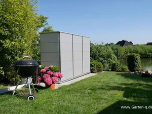 . Garten mit Grill, Pflanzkübel mit Blumen, grauem Schrank, Rasenfläche und Teich im Hintergrund.