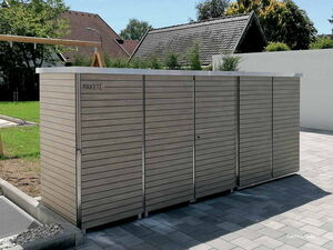 . Ein moderner Holzschuppen mit der Aufschrift "Pakete" steht auf einem gepflasterten Bereich in einem Garten.
