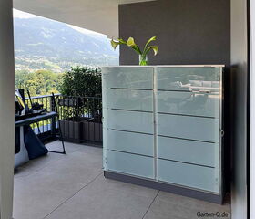 . Ein Balkon mit Bergblick, modernen Möbeln, Glasregal und Pflanze.