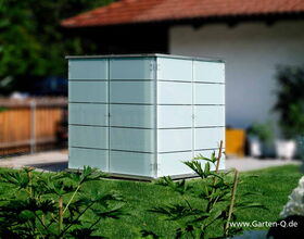 The image shows a garden storage box or shed, placed on a lawn. It has a modern, sleek design with horizontal panels and appears to be made from a material like metal or composite. In the foreground, there are green plants, and in the background, there is a building with a wooden railing. The website "www.Garten-Q.de" is visible in the bottom right corner, indicating a connection to garden products or storage solutions.