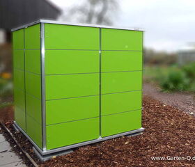 . Ein grünes Gartenschrank in modernem Design steht im Freien auf Mulch.