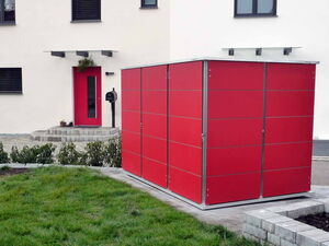 . Ein rotes Gartenhaus steht vor einem weißen Gebäude mit einer roten Tür und Garten.
