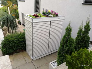 . Ein Gartenschrank mit bepflanztem Dach in einem modernen Garten mit Pflanzen und Statuen.