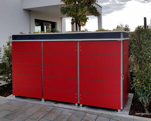 Ein roter, moderner Gartenschrank steht draußen neben einem Haus.