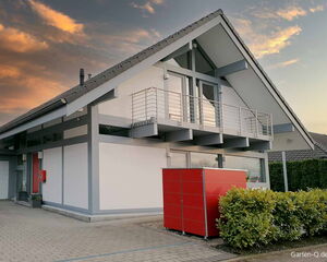 Modernes Haus mit Balkon, rote Wandverkleidung, Pflanzkübel und Abendhimmel im Hintergrund.